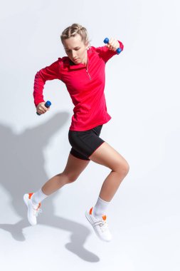 Kırmızı uzun kollu beyaz kadın ve beyaz halterli koşu kıyafetleriyle atlayan. Dikey Resim Yönlendirmesi