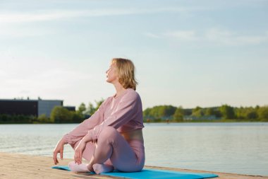 Ağaç sahnesinde kapalı gözlerle yoga yaparken olgun, beyaz bir kadını rahatlatıyordum. Yatay Görüntü