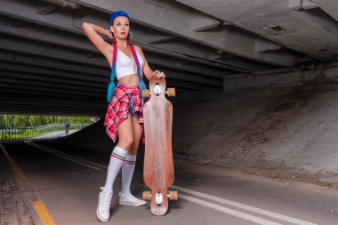 Grunge Garaj Ortamı ve Giyinme Şapkası ve Güneş Gözlükleri 'nde Uzun Tahtalı Kadın Kaykaycı Pozisyonu. Yatay Görüntü Yönlendirme