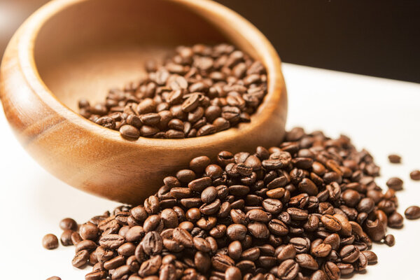 Куча коричневых кофейных зерен в деревянном кубке на белой Сурфе
