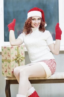Christmas, New Year, X-Mas Concepts and Celebrations. Young Caucasian Santa Helper Girl With Big Present Box. Posing as Snow Maiden in Santa Hat