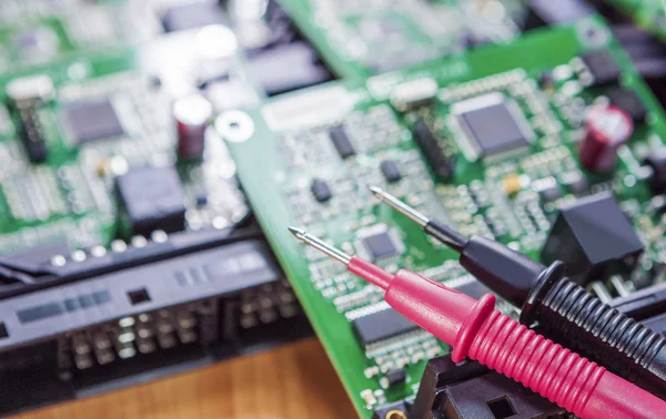 Laboratory Components and Staff. Pins of Digital Multimeter In Front of Printed Circuit  Boards with Integrated Circuitry