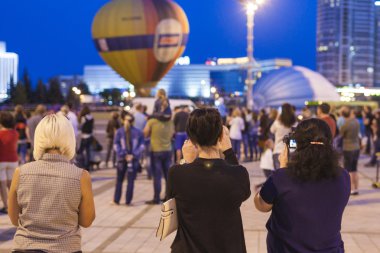 Minsk-Belarus, July 19, 2015: Three Girlfriends Taking Pictures of Air-Balloons During Night Show and Glowing of Air-Balloon on  International Aerostatics Cup