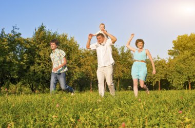 Family Concept and Ideas. Happy Family of Four Running Together Outside in Green Summer Forest.