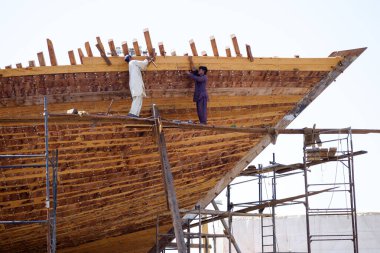 Hintli ve Bengalli işçiler, 13.10.2014 tarihinde Dubai, BAE 'de eski ahşap gemileri ve Dhows teknelerini tamir ediyor.