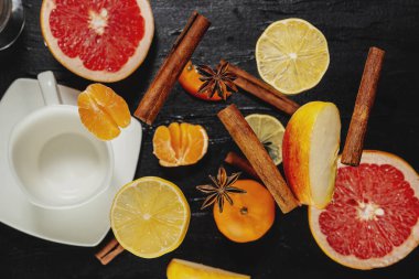 Siyah arka planda tarçın ve turunçgiller. Noel kokuları. Elma, tarçın ve mandalina. Dilimlenmiş meyve. Dünya gelenekleri. Tarçın çubuğu ve limon.