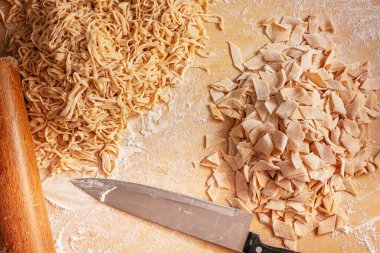 Dilimlenmiş makarna ve bıçak. Ev yapımı makarna, un ve yumurta hamuru. Et suyu için makarna hazırlıyorum. Leh mutfağı lezzetleri. Geleneksel Polonya Pazar öğle yemeği.