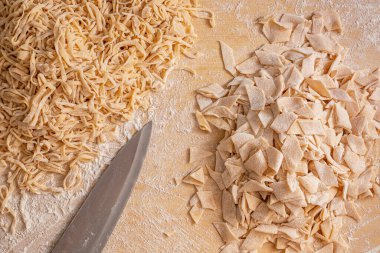 Dilimlenmiş makarna ve bıçak. Ev yapımı makarna, un ve yumurta hamuru. Et suyu için makarna hazırlıyorum. Leh mutfağı lezzetleri. Geleneksel Polonya Pazar öğle yemeği.