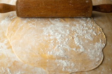 Makarna hamuru ve tahta bir raptiye. Köy evi. Ev yapımı makarna, un ve yumurta hamuru. Et suyu için makarna hazırlıyorum. Leh mutfağı lezzetleri. Geleneksel Polonya Pazar öğle yemeği.