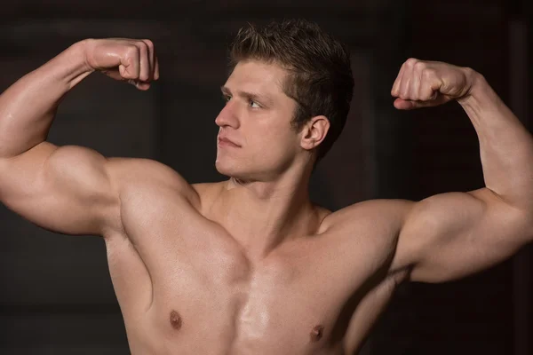 Joven saludable mostrando sus bíceps bien entrenados — Foto de Stock