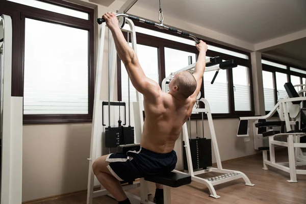 Young Man Doing Back Exercise on a Machine — Stock Photo, Image