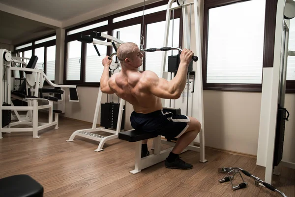 Joven haciendo ejercicio de espalda en una máquina —  Fotos de Stock