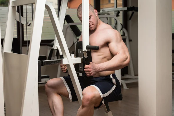 Joven haciendo ejercicio de espalda en una máquina — Foto de Stock