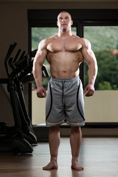 Junger Mann lässt Muskeln im Fitnessstudio spielen — Stockfoto