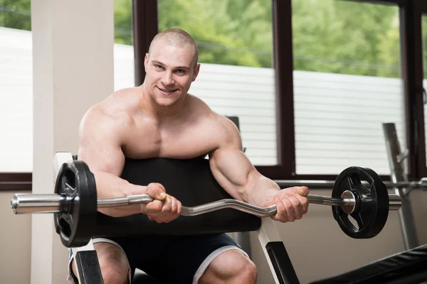 Man in de sportschool uitoefening biceps met barbell — Stockfoto