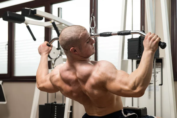 Joven haciendo ejercicio de espalda en una máquina —  Fotos de Stock