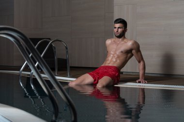 Kollarını havuzu kenarında oturan adam