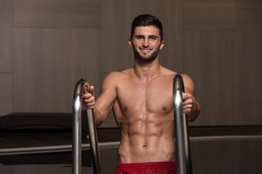 Kollarını havuzu kenarında oturan adam