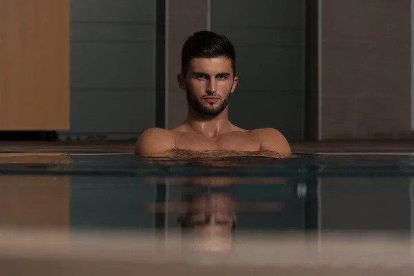 Junger Mann schwimmt in Pool an Ferienanlage — Stockfoto
