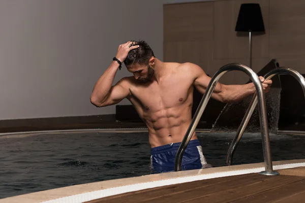 Hombre descansando sus brazos al borde de la piscina —  Fotos de Stock