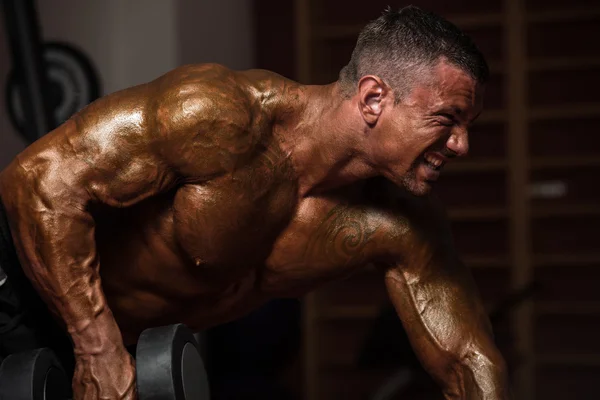 Bodybuilder trainiert Rücken mit Kurzhanteln — Stockfoto