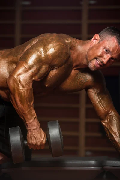 Bodybuilder Exercising Back With Dumbbells — Stock Photo, Image