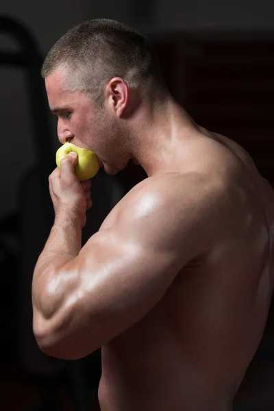 Людина культурист, з'ївши яблуко — стокове фото