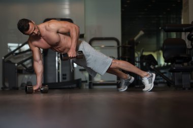 İtme yaparken vücut geliştirmeci Ups katta Dumbbells ile