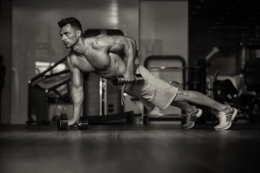 Genç adam yapıyor Push Ups Dumbbells ile katta
