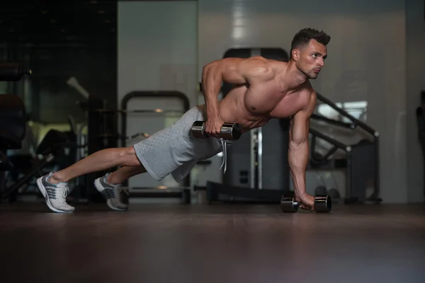 Bodybuilder doet Push Ups met halters op verdieping — Stockfoto