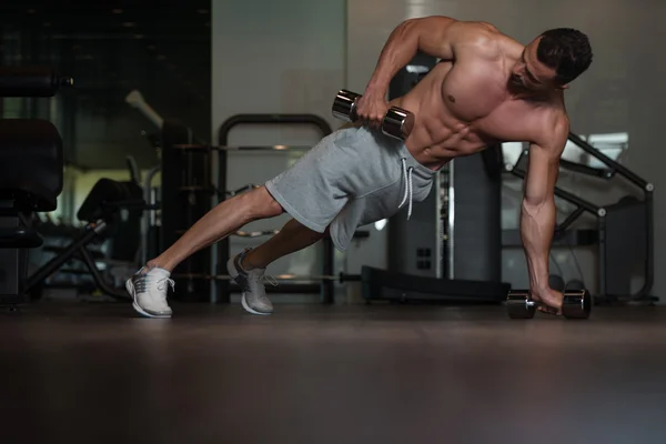 Bodybuilder göra Push Ups med hantlar på golvet — Stockfoto