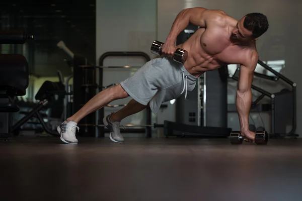 Fisiculturista fazendo Push Ups com halteres no chão — Fotografia de Stock