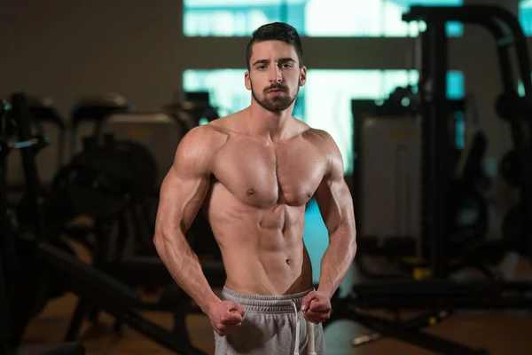 Uomo muscolare che flette i muscoli in palestra — Foto Stock