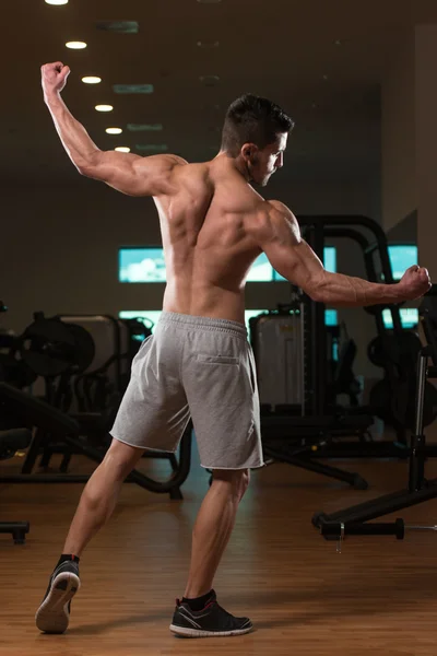 Homem muscular flexionando músculos no ginásio — Fotografia de Stock