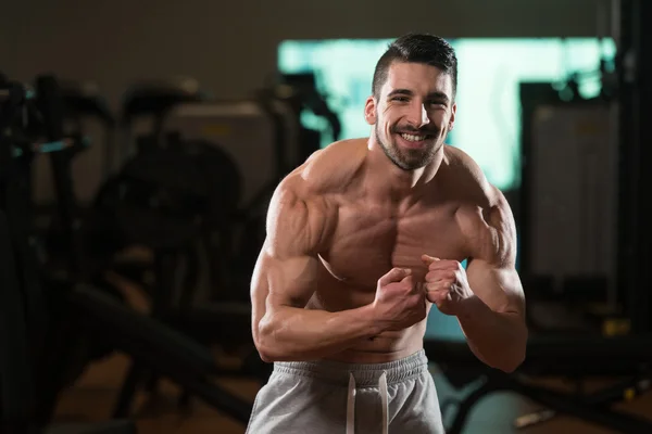 Gespierde man buigen spieren in de sportschool — Stockfoto