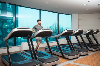 Genç adam bir koşu bandı üzerinde egzersiz