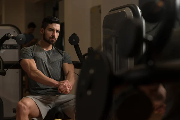 Atlético homem mostrando seus músculos no ginásio — Fotografia de Stock