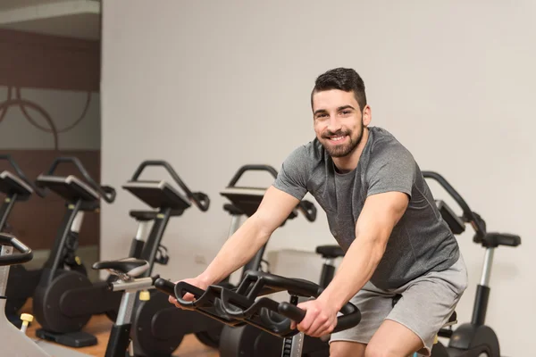 Homme musculaire faisant du vélo dans un centre de remise en forme moderne — Photo