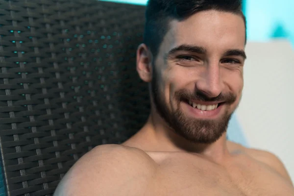 Hombre descansando en tumbonas junto a la piscina — Foto de Stock