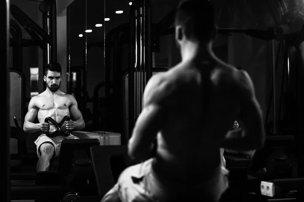 Joven haciendo ejercicio de espalda en una máquina —  Fotos de Stock