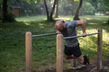 Kaslı adam egzersiz çubuklarında açık spor salonunda