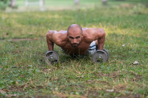 Giovane uomo fare stampa up con manubri all'aperto — Foto Stock