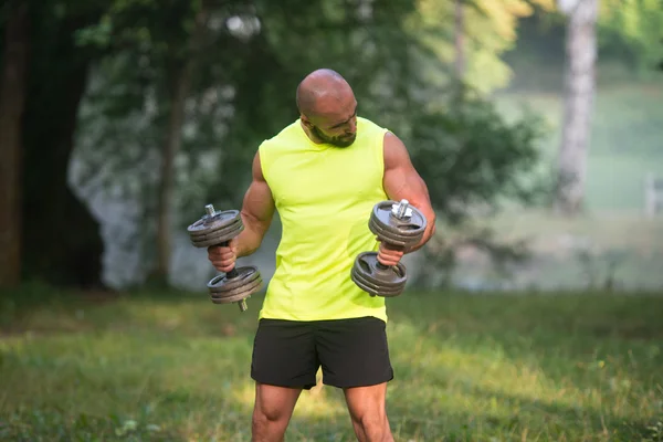 Jonge Man oefening met halters buiten training — Stockfoto