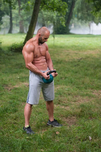 Przystojny mięśni mężczyzna trzyma czajnik Bell — Zdjęcie stockowe