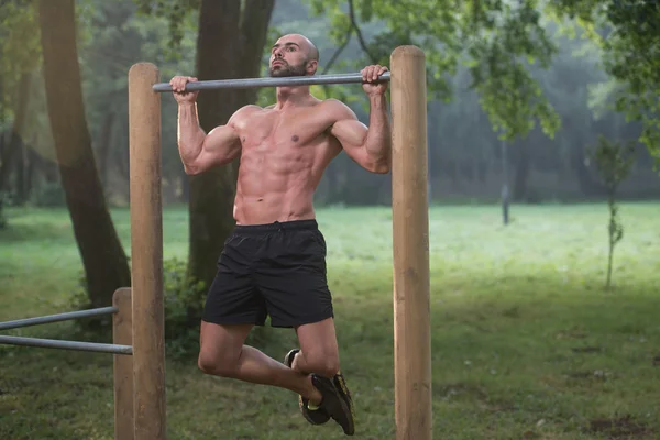Entraînement d'homme musculaire sur des barres dans la salle de gym extérieure — Photo