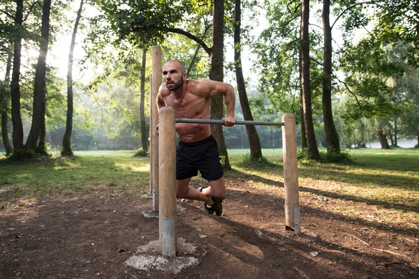 Hombre ejercitándose en barras paralelas al aire libre —  Fotos de Stock