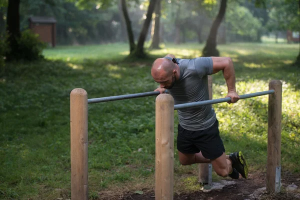 Treino de homem muscular em bares no ginásio ao ar livre — Fotografia de Stock