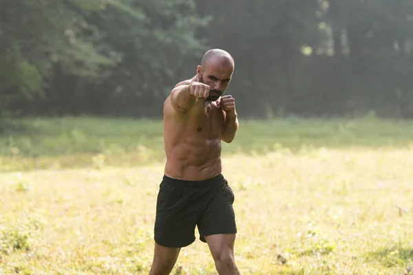 Dospělý muž boxerský trénink venku v parku — Stock fotografie