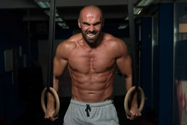 Muskulöser Mann hält Turnringe — Stockfoto