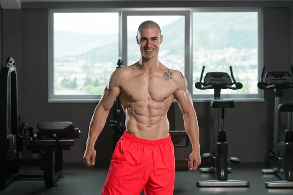 Musculoso hombre flexionando los músculos en el gimnasio —  Fotos de Stock